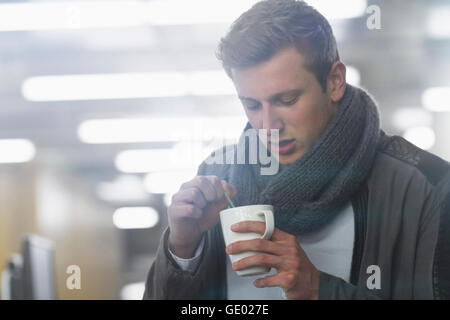 Young businessman drinking coffee and working till late night in office, Freiburg im Breisgau, Baden-Württemberg, Germany Stock Photo