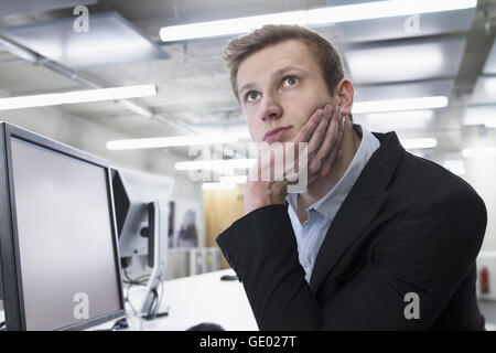 Young businessman thinking and working till late night in office, Freiburg im Breisgau, Baden-Württemberg, Germany Stock Photo