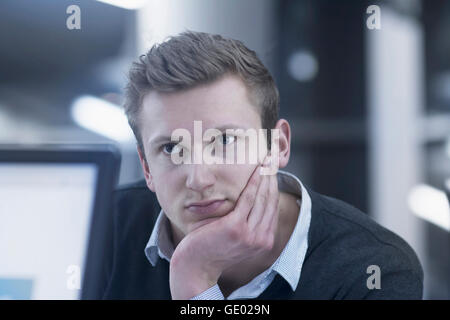 Young businessman thinking and working till late night in office, Freiburg im Breisgau, Baden-Württemberg, Germany Stock Photo