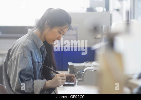 Female technician soldering electronic components in an industrial plant, Freiburg Im Breisgau, Baden-württemberg, Germany Stock Photo