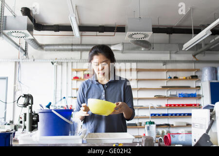 Young female engineer looking into pan in an industrial plant, Freiburg im Breisgau, Baden-Württemberg, Germany Stock Photo