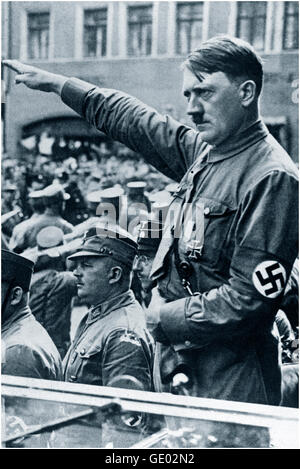 Adolf Hitler in open car wearing Sturmabteilung uniform and swastika armband performing Nazi salute at a political rally parade in Germany 1930's.  The Sturmabteilung SA; literally 'Storm Detachment') was the Nazi Party's (National Socialist German Workers' Party) original paramilitary wing. It played a significant role in Adolf Hitler's rise to power in the 1920s and 1930s. Its primary purposes were providing protection for Nazi rallies and assemblies, disrupting the meetings of opposing parties. Stock Photo