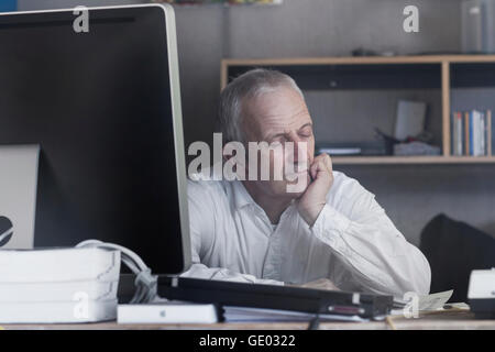 Senior businessman sitting in the office and sleeping, Freiburg im Breisgau, Baden-Württemberg, Germany Stock Photo