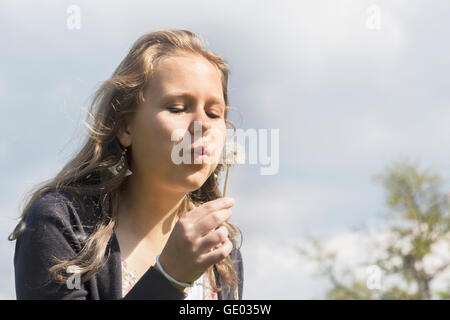 Teenage girl blowing dandelion flower, Freiburg im Breisgau, Baden-Württemberg, Germany Stock Photo