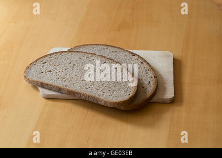Two slices of brown bread on chopping board on the table Stock Photo