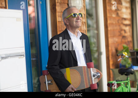 Senior businessman wearing suit and holding longboarding, Freiburg im Breisgau, Baden-Württemberg, Germany Stock Photo