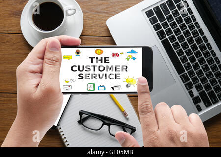 THE CUSTOMER SERVICE (Target Market Support Assistance) message on hand holding to touch a phone, top view, table computer coffe Stock Photo