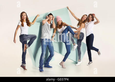 Group of friends with big arrow. Team of young people dressed in blue jeans and a white t-shirt with a big mock-up shots. Stock Photo