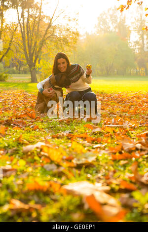 Beautiful young woman playing with her Dog in the Park in the autumn. Stock Photo