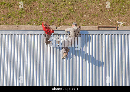 Szczecin, Poland - April 07, 2016: Two men working on a store roof made of corrugated metal sheets, picture taken from above. Stock Photo