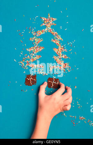 Symbols of Christmas tree and gifts made of colored sprinkles on blue background Stock Photo