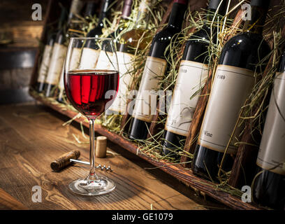 Glass of red wine and wine bottles on the background. Stock Photo