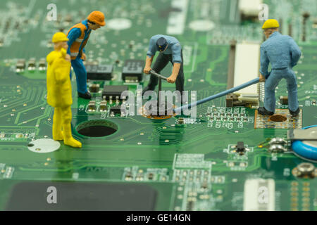 mini workers team try to remove screw from green mainboard - can use to display or montage on products Stock Photo
