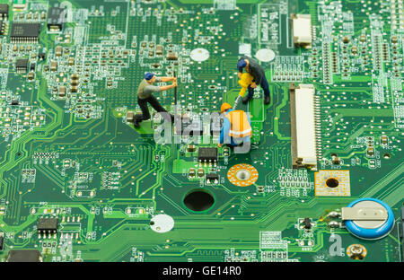 mini workers team try to maintain chip on mainboard - can use to display or montage on products Stock Photo