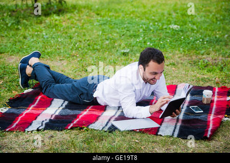 Young business man reading book outside in a park Stock Photo