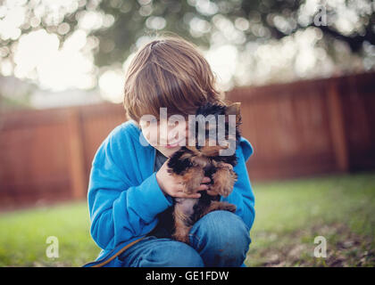 Boy cuddling his yorkie puppy dog Stock Photo