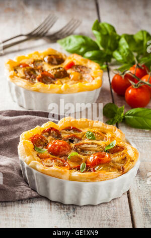 Quiche with cherry tomatoes on a rustic wooden table. Stock Photo