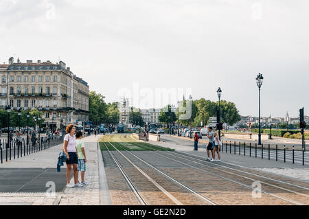 Bordeaux, France - July 25, 2014: Tourists crossing the tracks of tram near riverside. Stock Photo