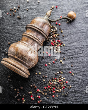 Colorful peppercorns and old pepper mill on the black background. Stock Photo