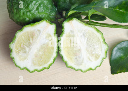 Bergamot (Other names are Kaffir lime, Citrus, Magnoliophyta, Bergamot, Rutaceae) fruits with leaf isolated on wooden plate Stock Photo