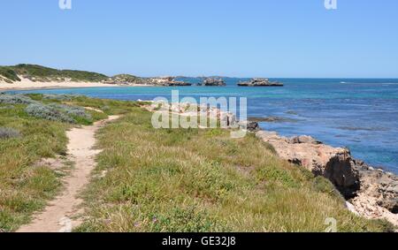 Narrow sandy path through the vegetated dunes at Point Peron with limestone rock, beach and Indian Ocean in Western Australia Stock Photo