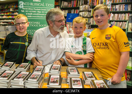 Cork, Ireland. 22nd July, 2016. Gerry Adams, the leader of Political Party Sinn Féin was in Liam Ruiseal's Bookshop in Oliver Plunkett Street, Cork, on Friday 22nd July, signing his new book - 'My Little Book of Tweets'. David, Luke and Seán Humphries-O'Mahony got their copy of the book signed by Mr Adams. Credit: Andy Gibson/Alamy Live News. Stock Photo