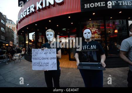 London, UK. 23rd July, 2016. Earthlings ,the London vegan action group ,stand silently in Leicester square before a burger outlet , displaying laptop videos of the meat industry . Credit:  Philip Robins/Alamy Live News Stock Photo