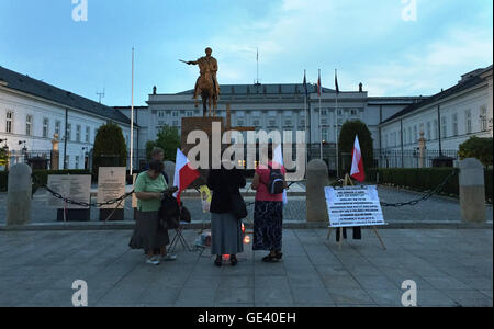 Warsaw, Poland. 12th July, 2016. Supporters of the national-conservative Law and Justice (PiS) party have errected a wooden cross outside the presidential palace in Warsaw, Poland, 12 July 2016. The sign the three women and one man have set up, in order not to be disturbed while praying, reads 'we pray for Poland and the truth about 10.04.2010'. PHOTO: NATALIE SKRZYPCZAK DPA/Alamy Live News Stock Photo