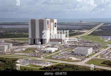 An aerial view of the Launch Complex 39 area shows the Vehicle Assembly Building (center), with the Launch Control Center on its right. On the west side (lower end) are (left to right) the Orbiter Processing Facility, Process Control Center and Operations Support Building. Looking east (upper end) are Launch Pads 39A (right) and 39B (just above the VAB). The crawlerway stretches between the VAB and the launch pads toward the Atlantic Ocean, seen beyond them. At right is the turning basin where new external tanks are brought via ship.  Image # : 99PP-1213 Stock Photo