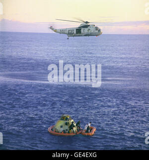 A Navy helicopter arrives to recover the Apollo 10 astronauts, seen entering a life raft, as the Command Module &quot;Charlie Brown&quot; floats in the South Pacific. U.S. Navy underwater demolition team swimmers assist in the recovery operations. Splashdown occurred at 12:53 p.m. eastern time, May 26, 1969, about 400 miles east of American Samoa. Note that in this photo the divers have attached a flotation collar to the spacecraft.  Image # : S69-21036 Date: May 26, 1969 Stock Photo