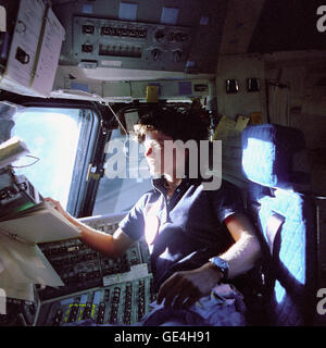 (June 1983) Astronaut Sally K. Ride, mission specialist on STS-7, monitors control panels from the pilot's chair on the Flight Deck. Floating in front of her is a flight procedures notebook.  Image # : S83-35783 Stock Photo