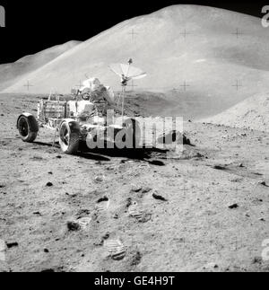 David R. Scott, Commander of Apollo 15, works at the Lunar Roving Vehicle (LRV) during the third lunar surface extravehicular activity (EVA) of the mission at the Hadley-Apennine landing site. Hadley Rille is at the right center of the picture. Hadley Delta, in the background, rises approximately 4,000 meters (about 13,124 feet) above the plain. St. George Crater is partially visible at the upper right edge. This photograph was taken by Lunar Module pilot James B. Irwin. This view is looking almost due South.   Image # : AS15-82-11121 Stock Photo