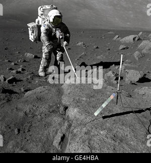 Geologist-Astronaut Harrison Schmitt, Apollo 17 lunar module pilot, uses an adjustable sampling scoop to retrieve lunar samples during the second extravehicular activity (EVA-2), at Station 5 at the Taurus- Littrow landing site. The cohesive nature of the lunar soil is born out by the &quot;dirty&quot; appearance of Schmitt's space suit. A gnomon is atop the large rock in the foreground. The gnomon is a stadia rod mounted on a tripod, and serves as an indicator of the gravitational vector and provides accurate vertical reference and calibrated length for determining size and position of object Stock Photo