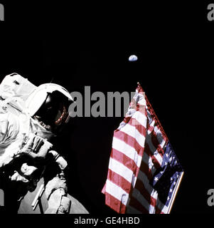 Geologist-Astronaut Harrison Schmitt, Apollo 17 Lunar Module pilot, is photographed next to the American Flag during extravehicular activity (EVA) of NASA's final lunar landing mission in the Apollo series. The photo was taken at the Taurus-Littrow landing site. The highest part of the flag appears to point toward our planet earth in the distant background.   Image # : AS17-134-20384  December 13, 1972 Stock Photo