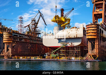 Big ship under repairing on floating dry dock in shipyard. Stock Photo