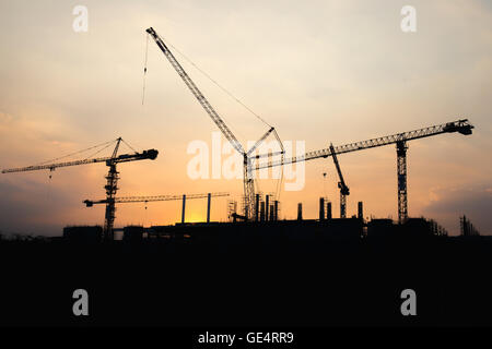 Industrial construction crane working and building at site on sunset time Stock Photo