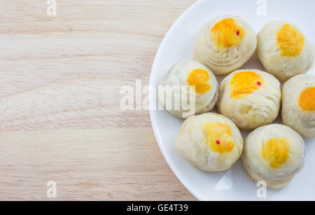 Chinese Pastry Mung Bean or Mooncake with Egg Yolk on dish and wooden table Stock Photo