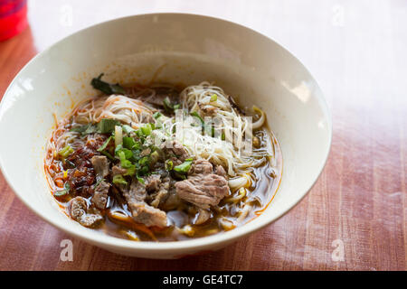 Bowl of noodles with vegetables on wooden table. delicious noodle. hot and sour soup original thai food. Tom Yum Stock Photo