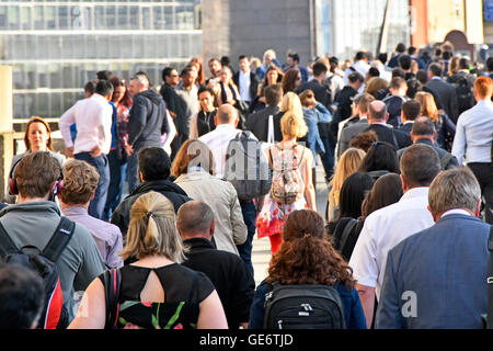 Commuter office workers walking across London Bridge towards London Bridge train station during commuters evening rush hour home England UK Stock Photo
