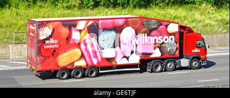 UK English motorway Wilkinson supply chain logistics via hgv articulated lorry & streamlined trailer with colourful Wilko graphics depicting sweets Stock Photo