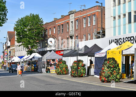 English town centre shopping High Street businesses with market stalls outside Marks and Spencer summer flower display & town clock Brentwood Essex UK Stock Photo