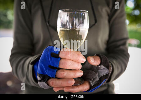 Woman cyclist holds glass of white wine during wine tasting session at the Chateau de Nitray in Athee-sur-Cher, France, 25 June 2008. Stock Photo