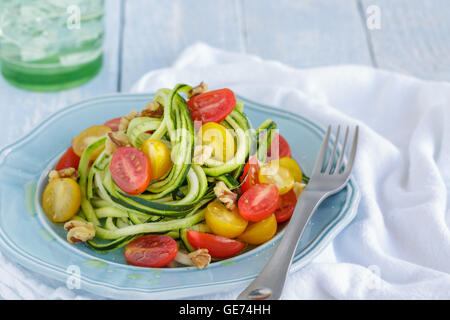 Zucchini noodles with tomatoes and walnuts tossed in olive oil Stock Photo