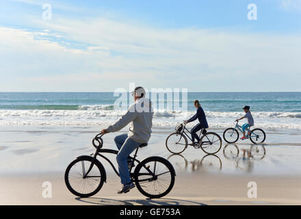 Family riding bikes on beach, San Diego, California Stock Photo