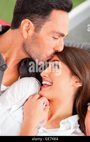 A photo of loving man kissing woman's forehead. Loving young male and female partners spending leisure time. They are at home. Stock Photo