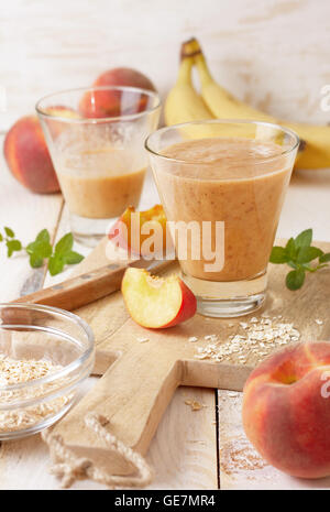 peach banana smoothie with oatmeal  in a glass,  fresh peaches on a wooden background Stock Photo