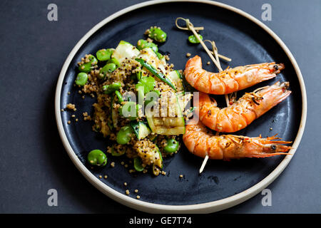Grilled tiger prawns with quinoa, courgettes and broad bean salad Stock Photo