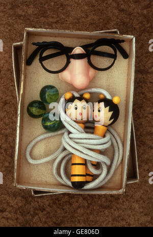 Joke false nose with plastic spectacles and eyebrows attached lying in box with novelty skipping rope Stock Photo