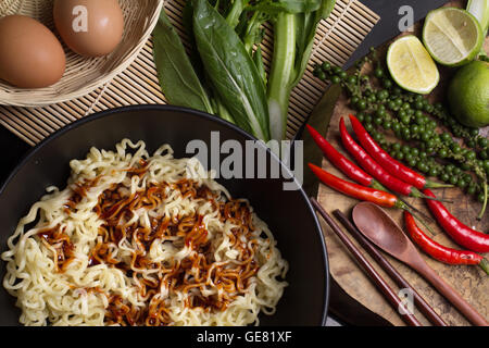 noodles in black bowl garnished on kitchen table Stock Photo