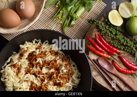 noodles in black bowl garnished on kitchen table Stock Photo